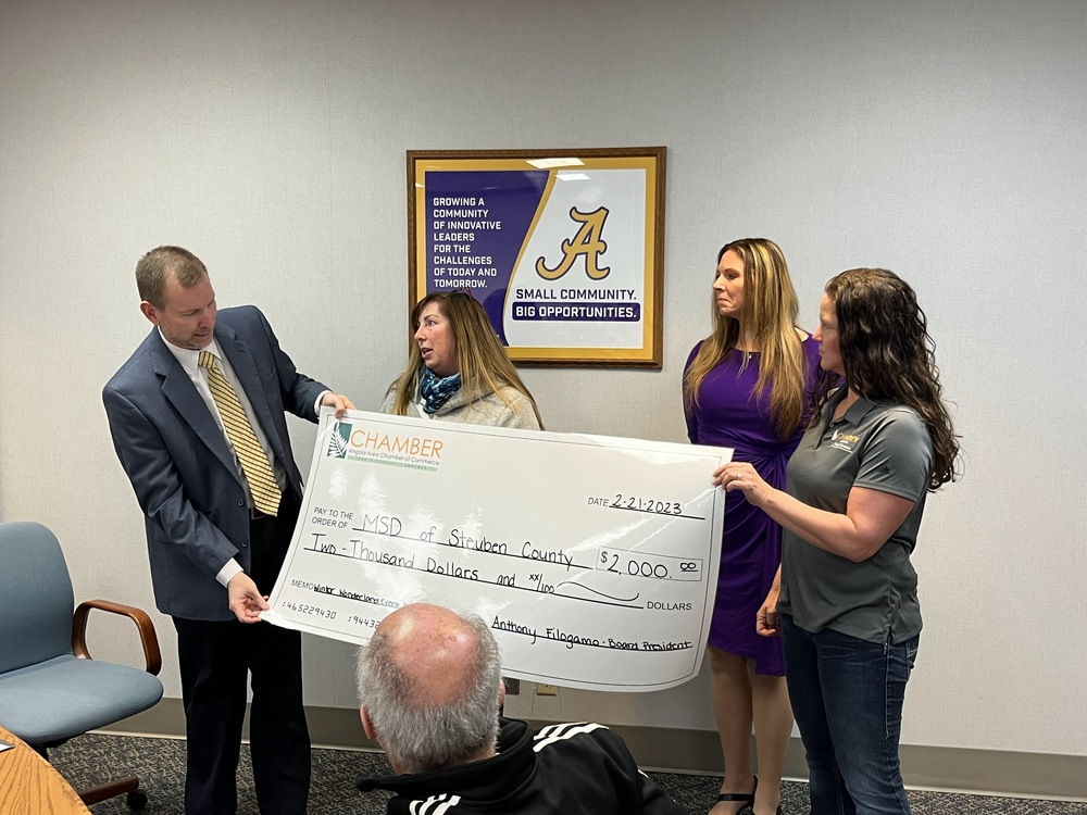 Dr. Widenhoefer stands with three members of the Angola Area Chamber of Commerce with a big presentation check