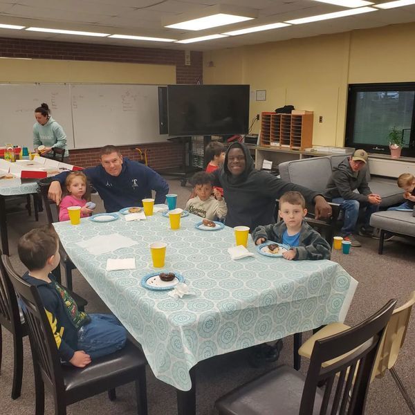 Dads and kids eat donuts at a table