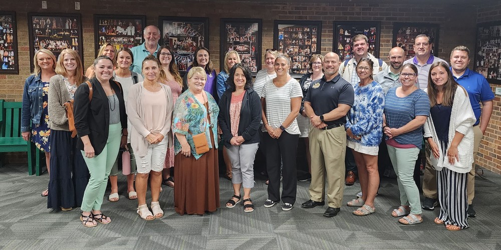 A group of male and female teachers and admins pose for a picture