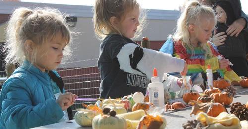 Students completing pumpkin crafts at a picnic table outside