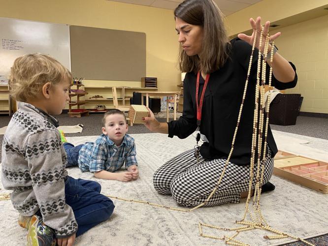 A teacher gives a lesson to two students using beads for counting