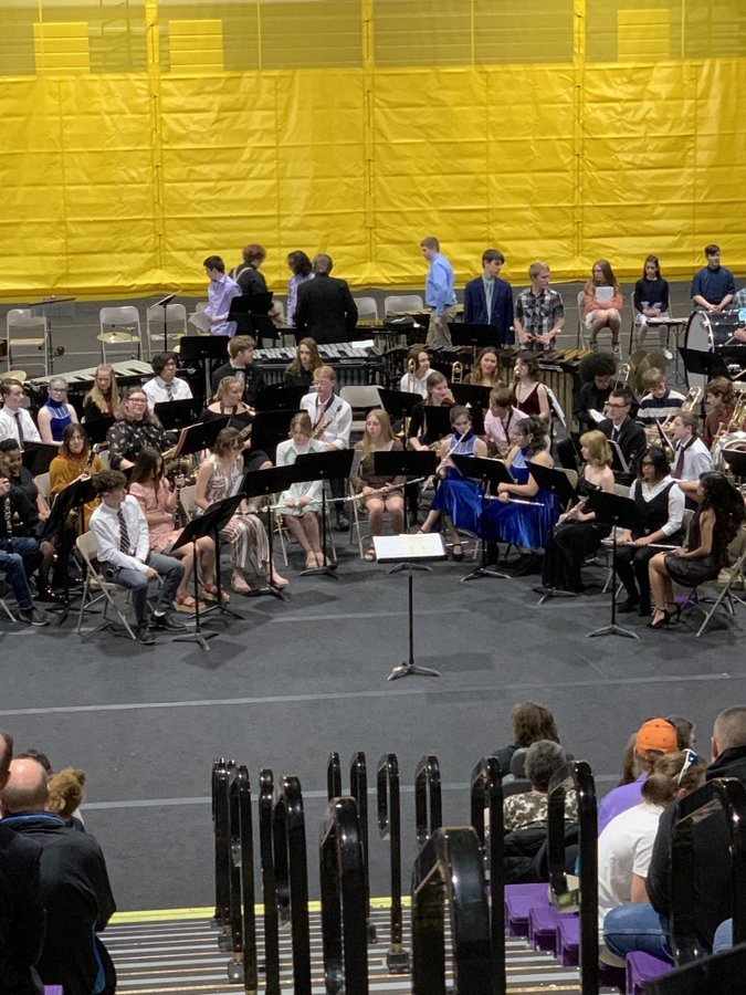 band students sitting on a stage, performing for an audience