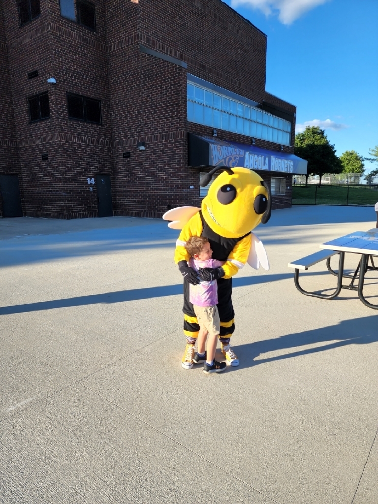 A little boy hugging a hornet mascot